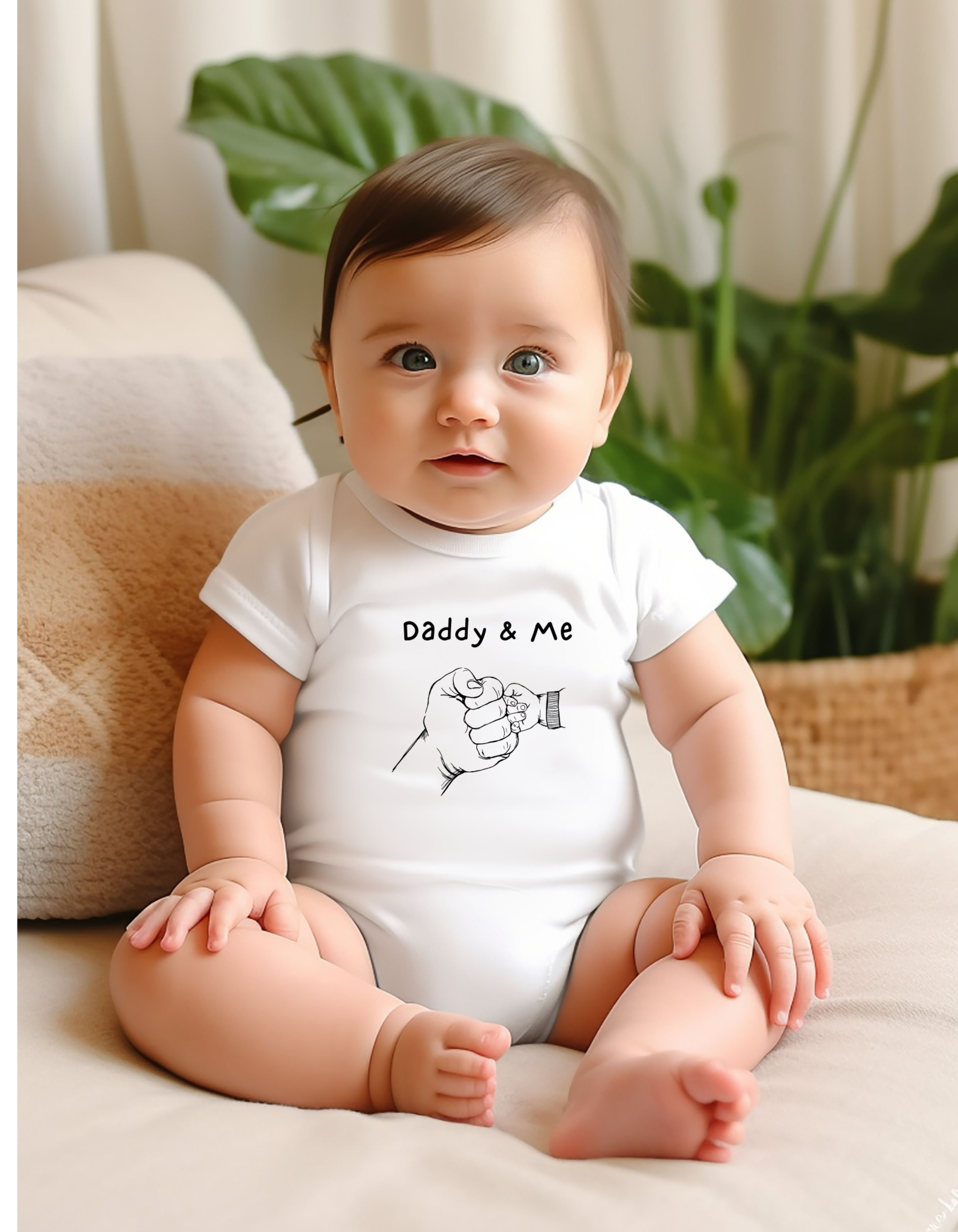 Infant boy wearing white onesie with "Daddy & Me" inspired fist bump graphic on front.