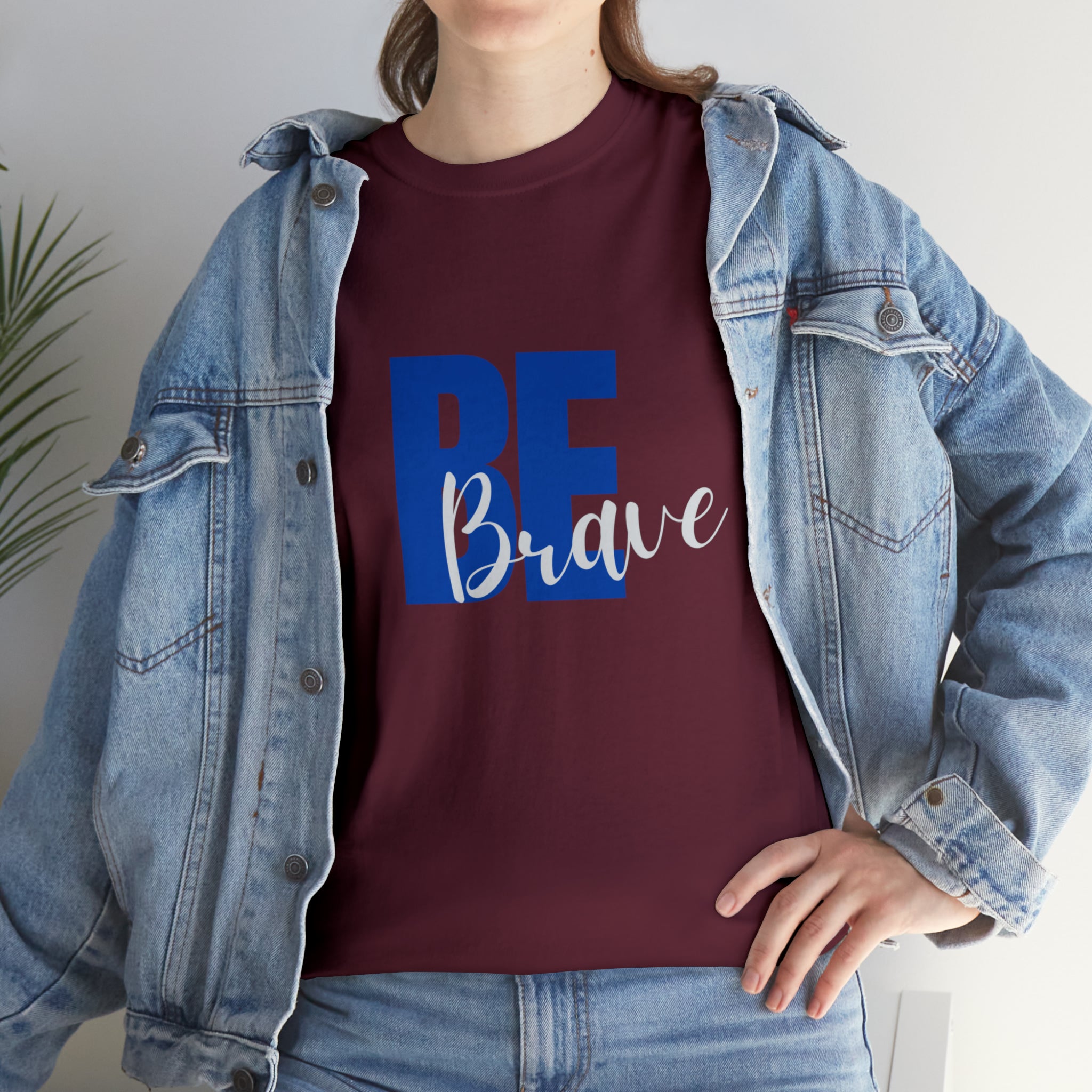 Adult women wearing maroon T-Shirt and Jean jacket with "Be Brave" motivational image on front.