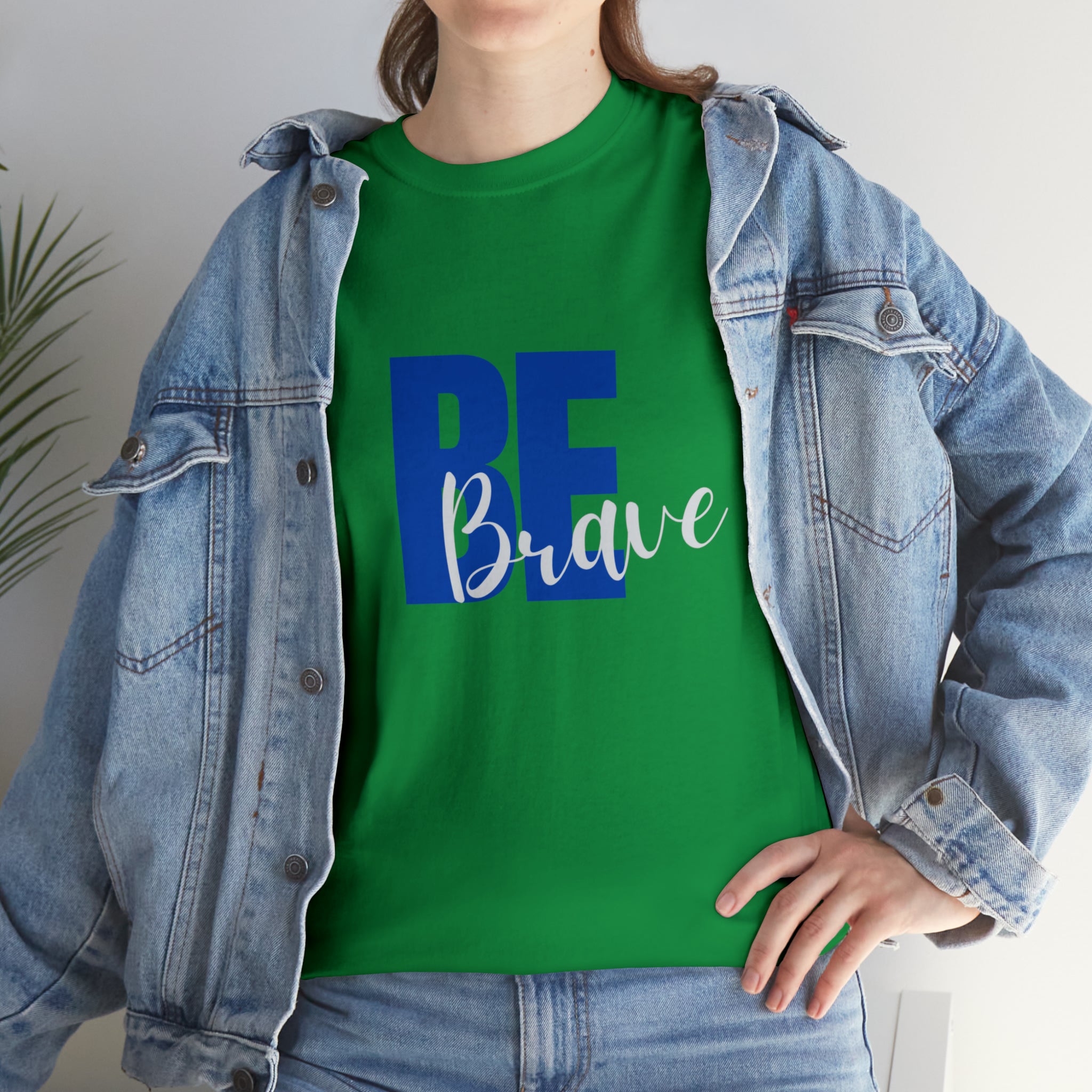 Adult women wearing turf green T-Shirt and Jean jacket with "Be Brave" motivational image on front.