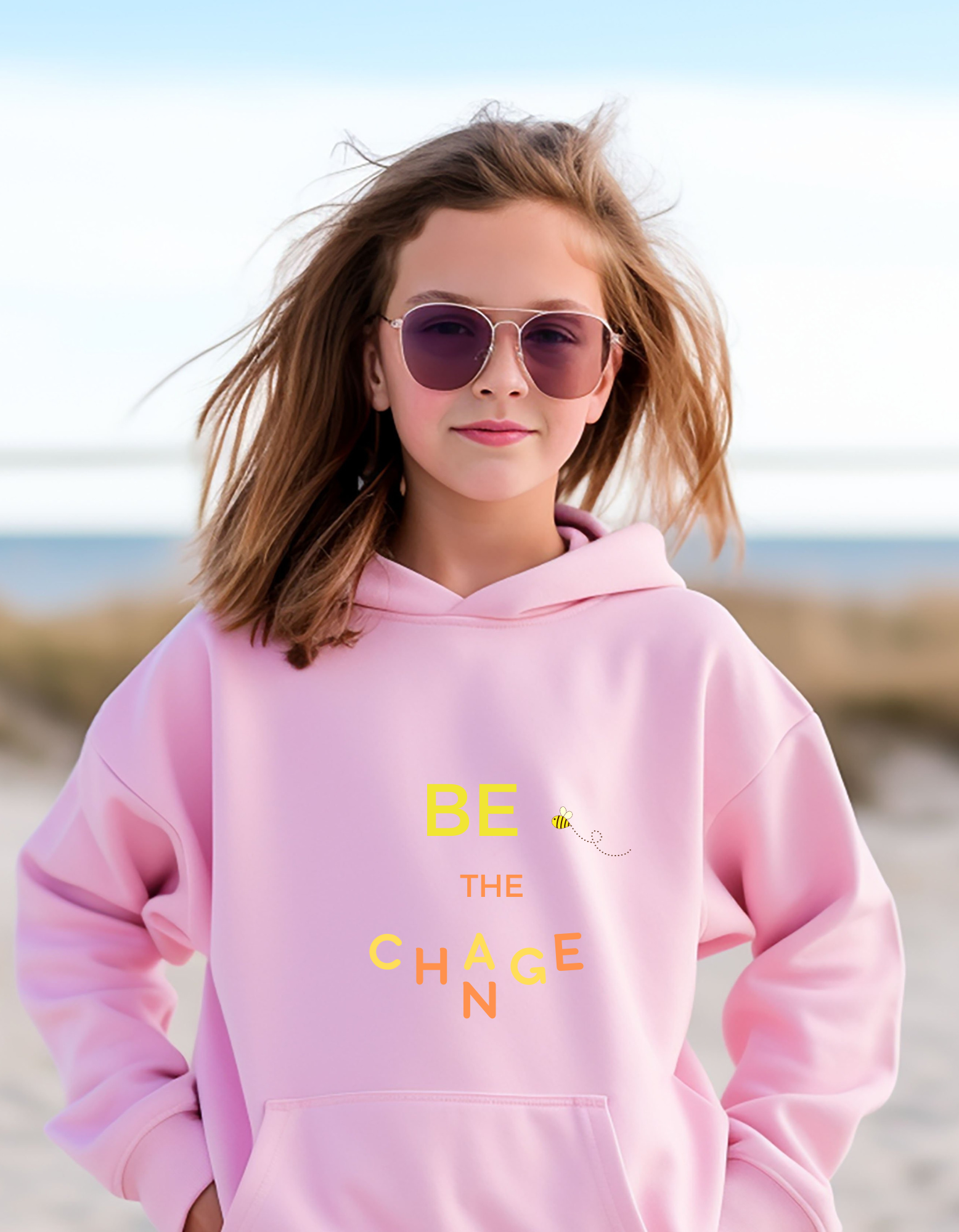 Youth girl wearing pink hoodie with "Be The Change" motivational image on front.